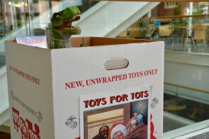 A T-Rex guards the Toys for Tots donation box.