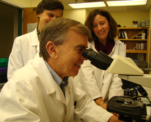 Dr. Richard Boucher examines a lung tissue sample while Drs. Claire Doerschuk and Wanda O'Neal look on. At right, Doerschuk presents information about the effect of chronic obstructive pulmonary disease (COPD) on the human lung.