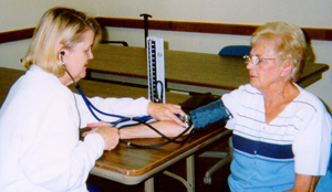 A public health nurse checks a woman's blood pressure during field work.