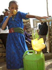 An Ethiopian girl drinks from a hand pump