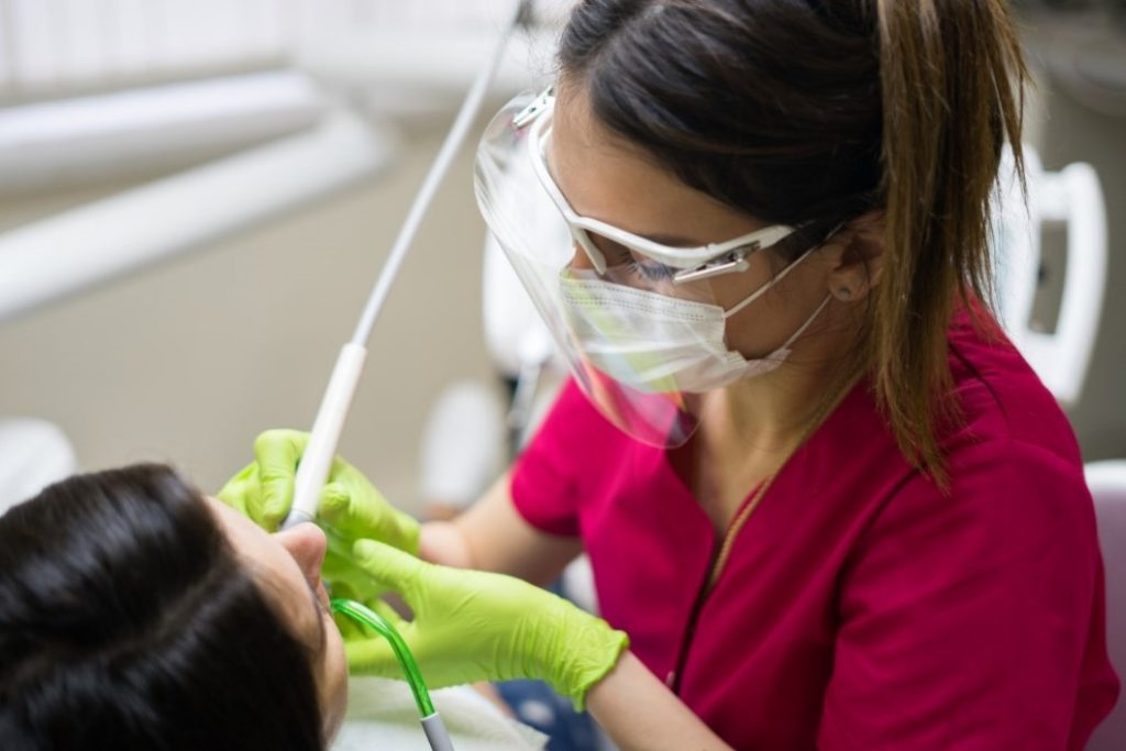 An oral health professional performs dental work on a patient