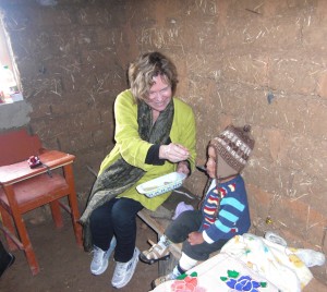 Dr. Peggy Bentley feeds a child in Peru. Taking a break from interviewing the child's mother about family feeding practices, Bentley introduces a snack prepared with an infant food grinder, a low-tech, inexpensive tool to provide young children with safe, nutritious food.