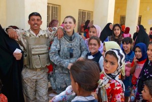 Shannon Niki Stroud (second from left) laughs with an Iraqi soldier and local schoolchildren during a humanitarian mission in Baghdad. (Photo credit: Capt. Jeff Wismann)