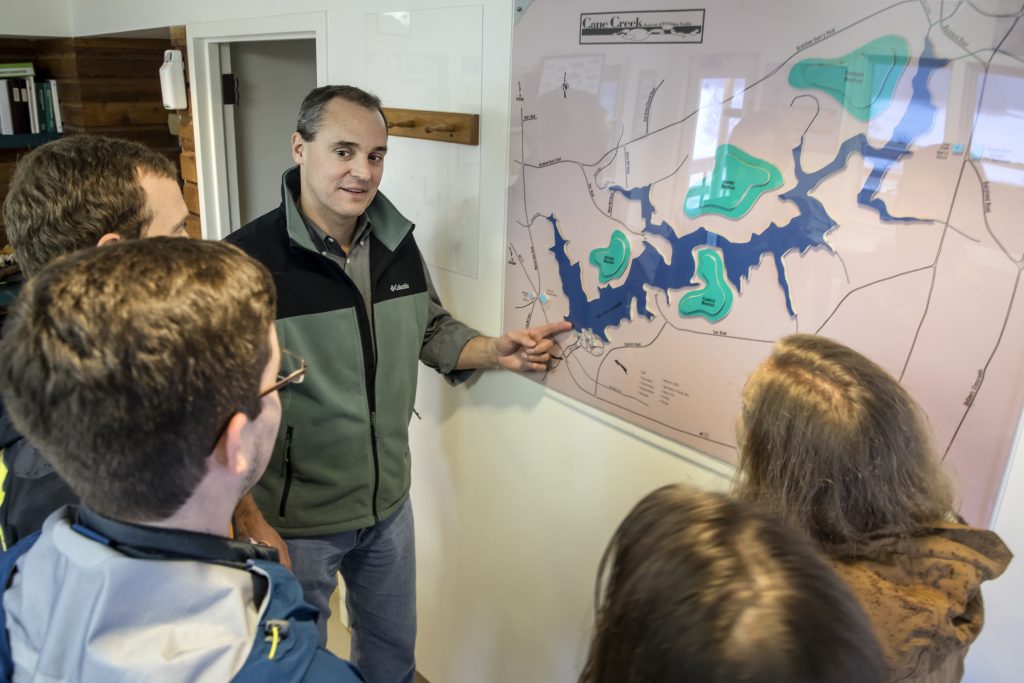 At Cane Creek Reservoir in Chapel Hill, N.C., Dr. Greg Characklis (at map) and his research group discuss reservoir management and its impact on water supply. (Photo by Johnny Andrews/UNC)
