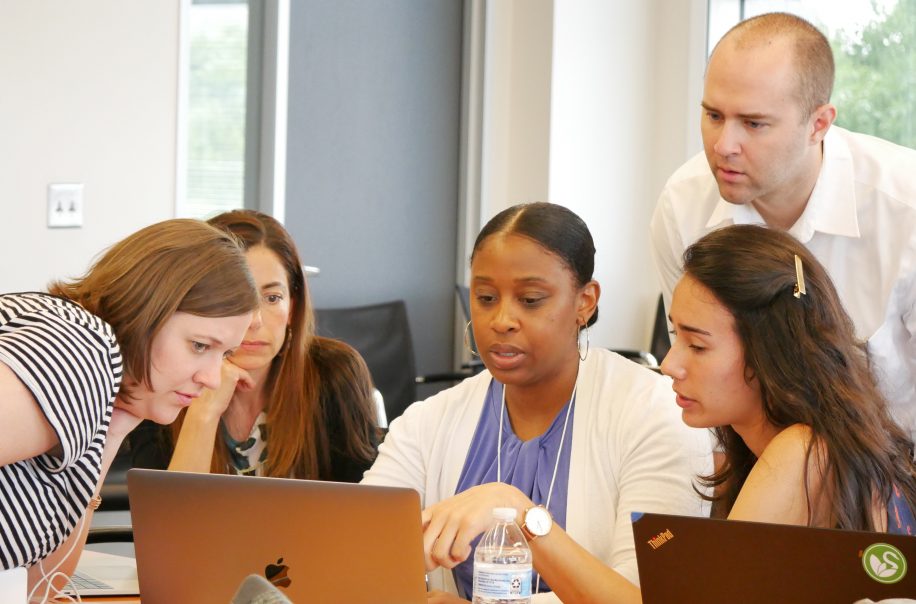 Trainees at an NCIPH workshop gather around a computer for an exercise