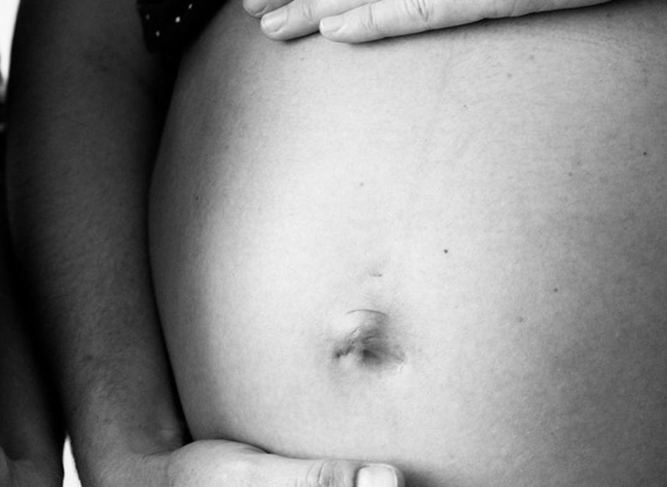 A women holds her pregnant belly.