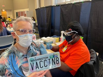 Dr. John Wiesman holds his Washington State license plate while receiving a COVID-19 vaccine in Durham County, North Carolina.