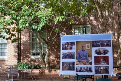 A poster on an easel in the Gillings courtyard with photos of Dr. Aitken