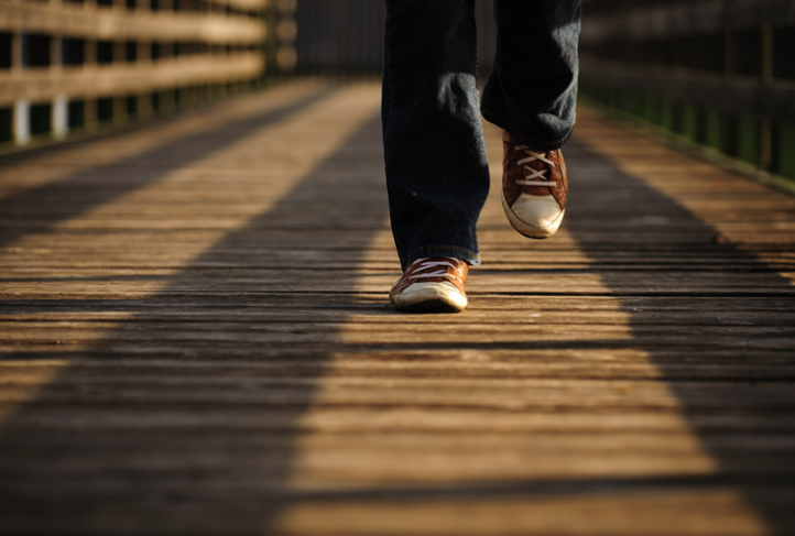 A person walks over a wooden bridge.