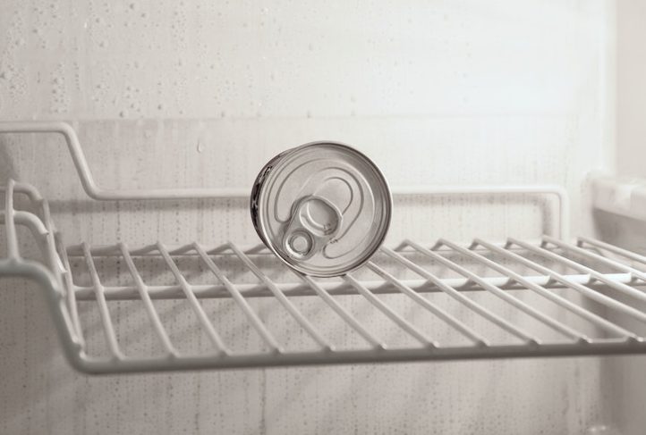 A can sits in an empty fridge.