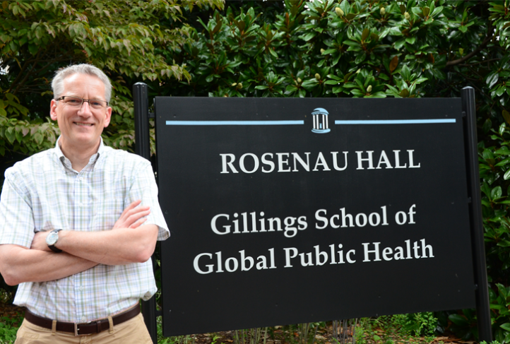 Dr. John Wiesman stands next to the Gillings School of Global Public Health sign outside Rosenau Hall.