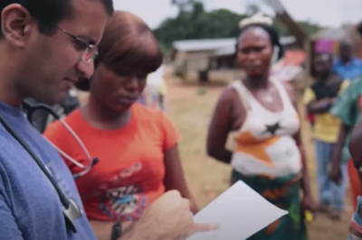 Dr. Raj Panjabi (left) — alongside a community health worker and nurse — sees a patient in a mining community in the rain forest of Liberia.