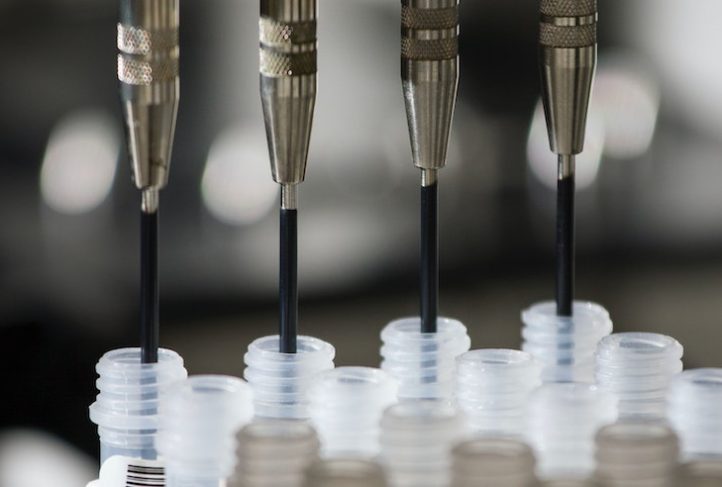 Syringes fill vials in a lab.
