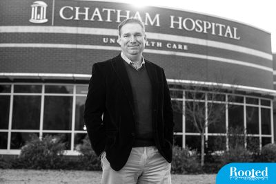 Dr. Mark Holmes stands in front of a rural hospital.