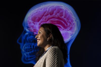 Dr. Tanya Garcia poses in front of an image of the human brain.