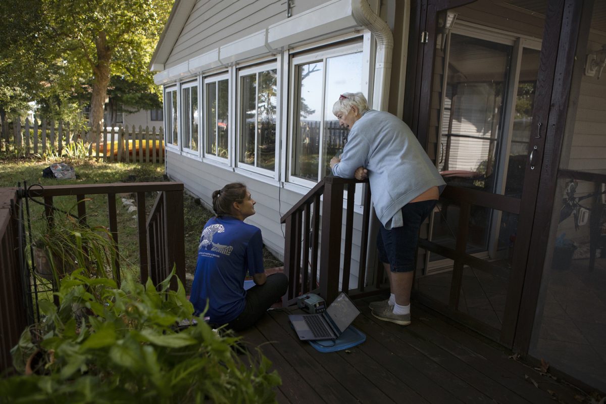 Haley Plaas chats with  Cathy Woody while downloading sensor data at her house.