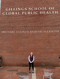 Helen stands in front of the brick wall surrounding the Michael Hooker Research Center
