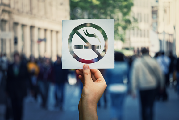 A person holds up a no smoking sign in a crowd.